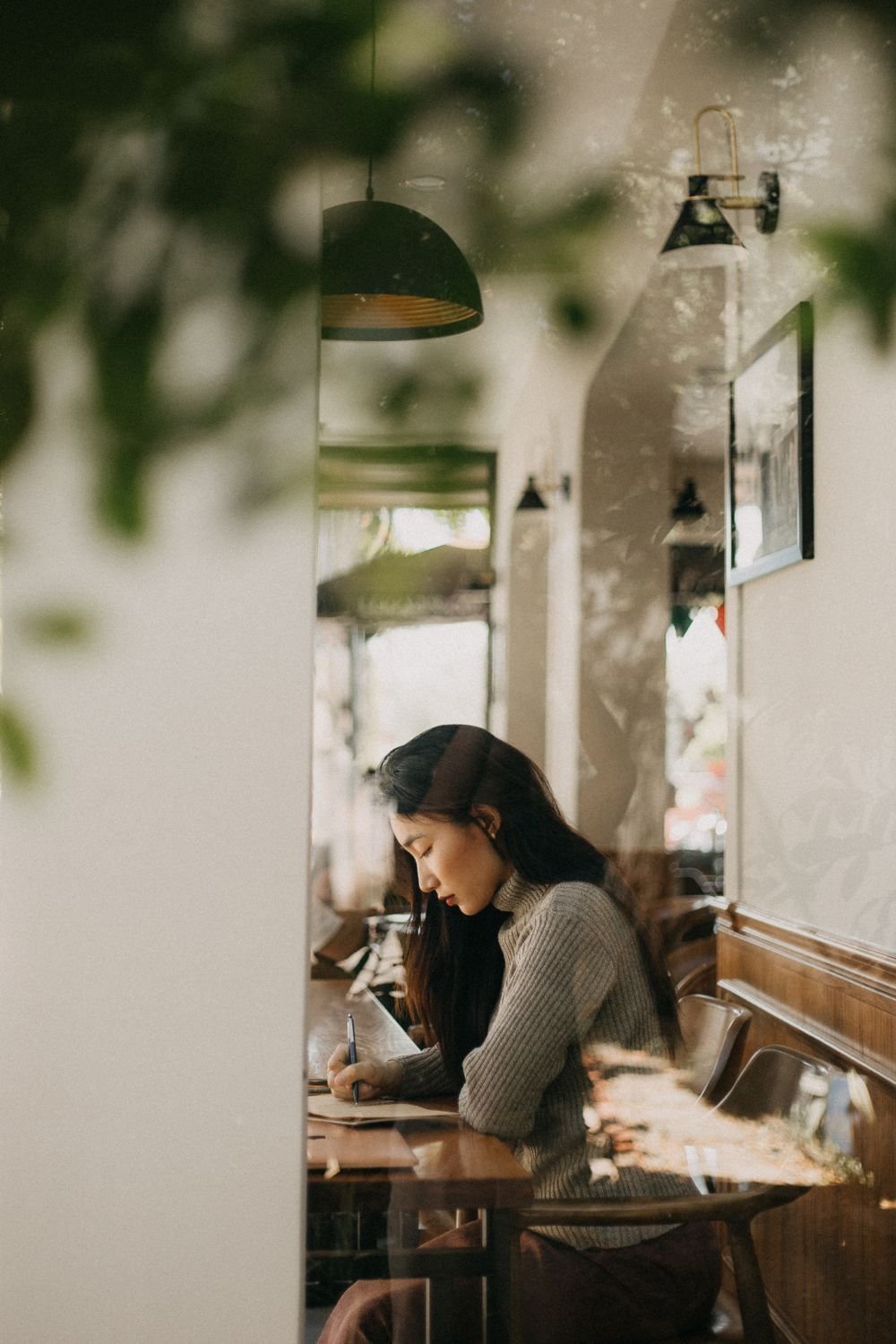 Persona estudiando alemán con café en una cafetería con plantas